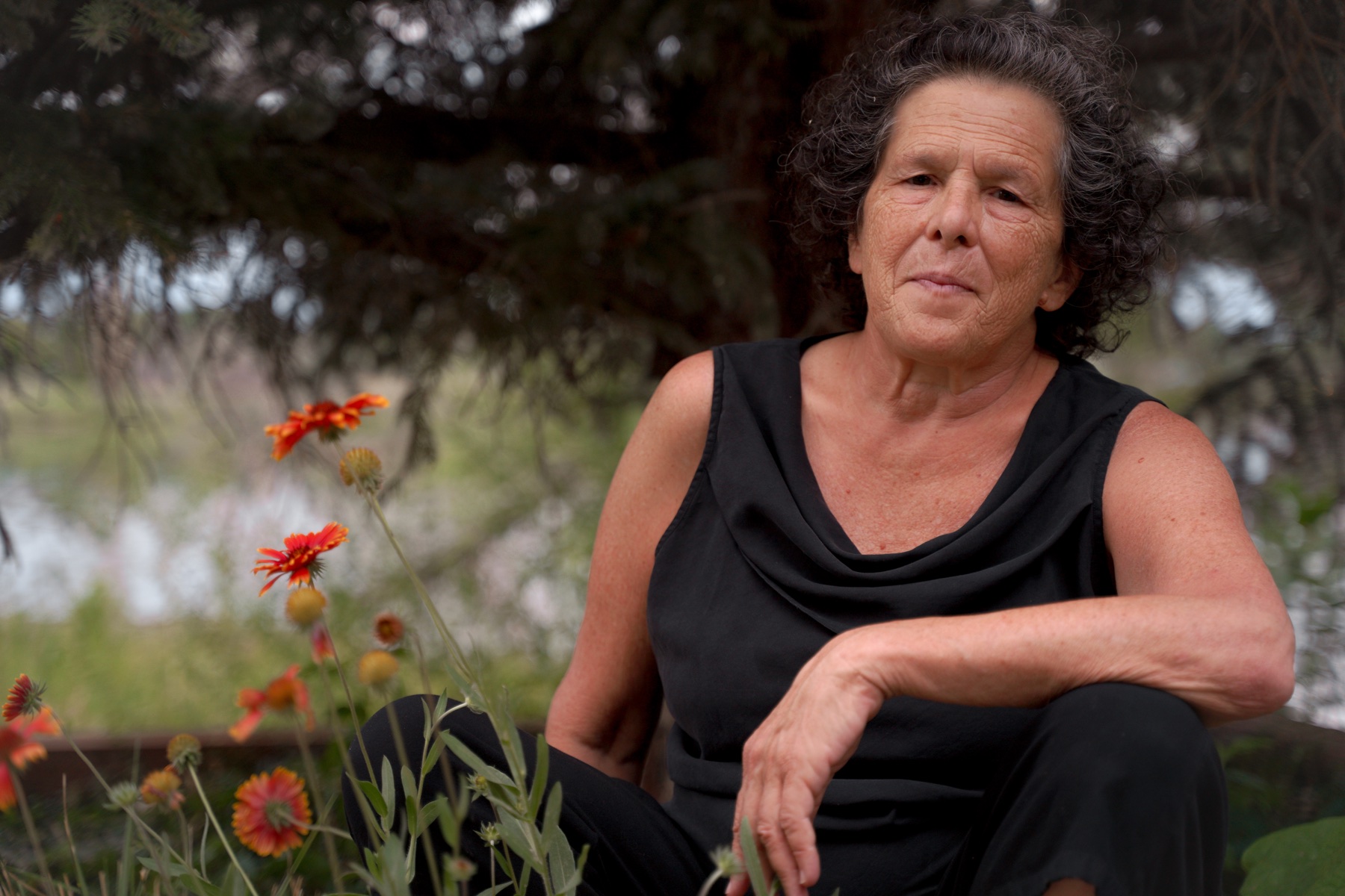 Amy Glin seated outdoors among orange flowers