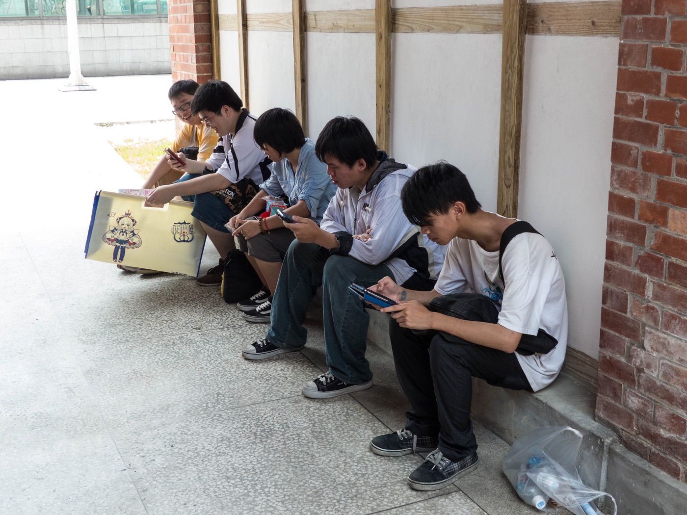 Several people sitting together while looking at their smartphones