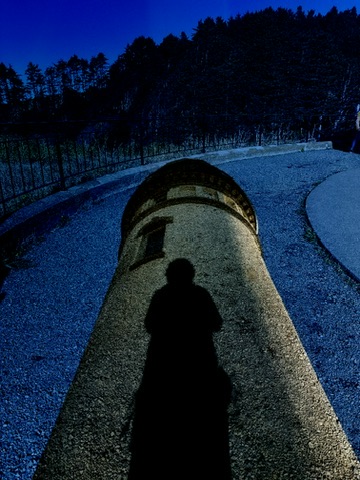 A person’s shadow on curved stone beneath a deep blue night sky