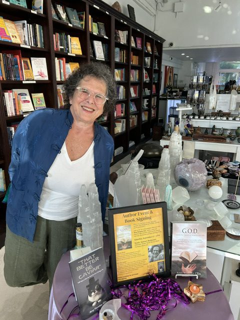 Amy Glin at an author event and book signing with copies of her books