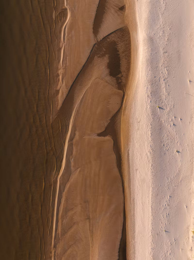 an aerial view of a sandy beach and a body of water