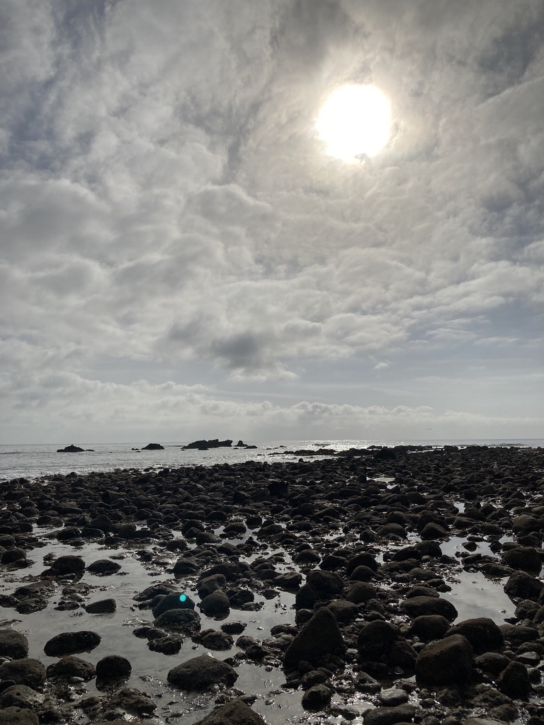 Sunlight through clouds over a rocky shoreline